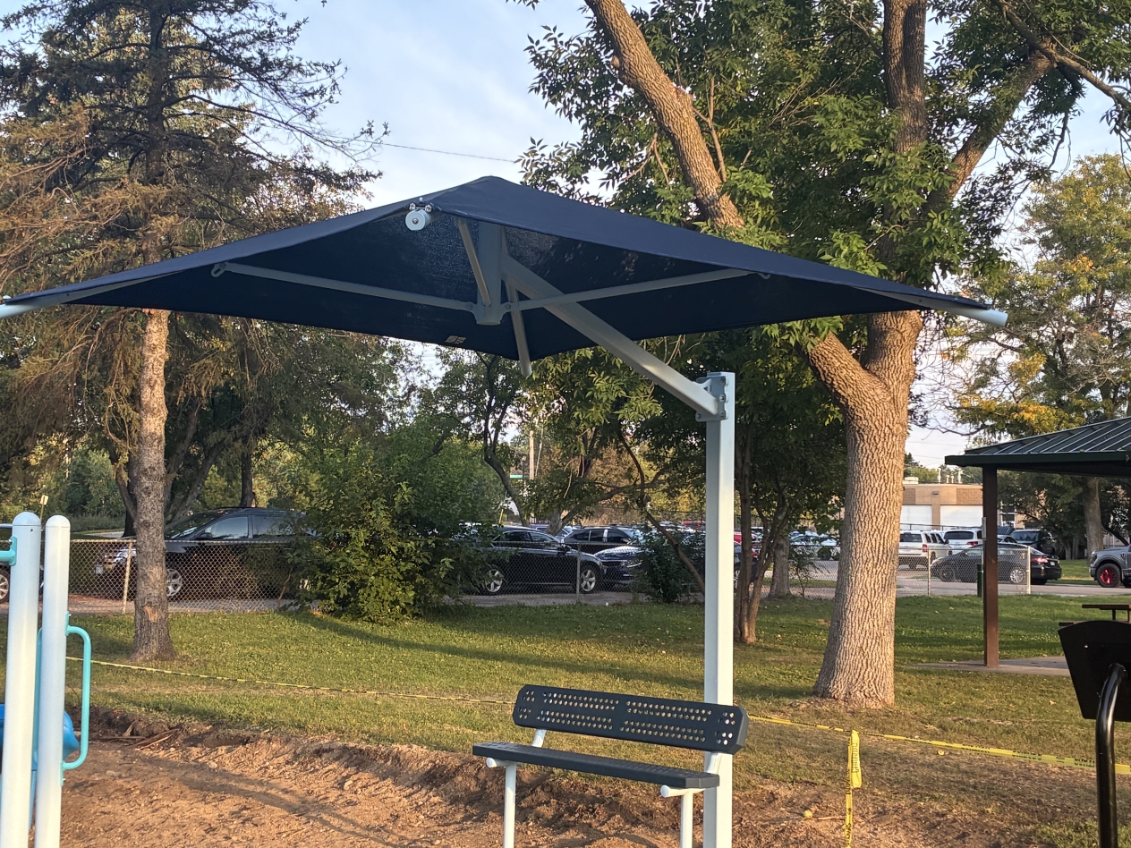 A blue shade canopy protects a bench at Ainsworth Park in St. Louis Park, Minnesota.