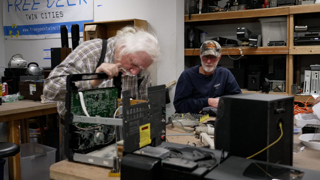 A Free Geek volunteer and community member sit together and examine a broken stereo