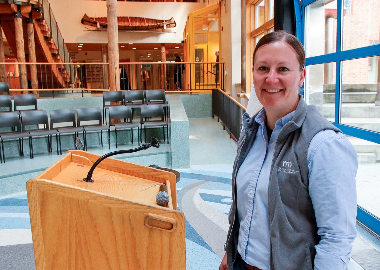 A woman standing in front of a lectern smiling at the camera.