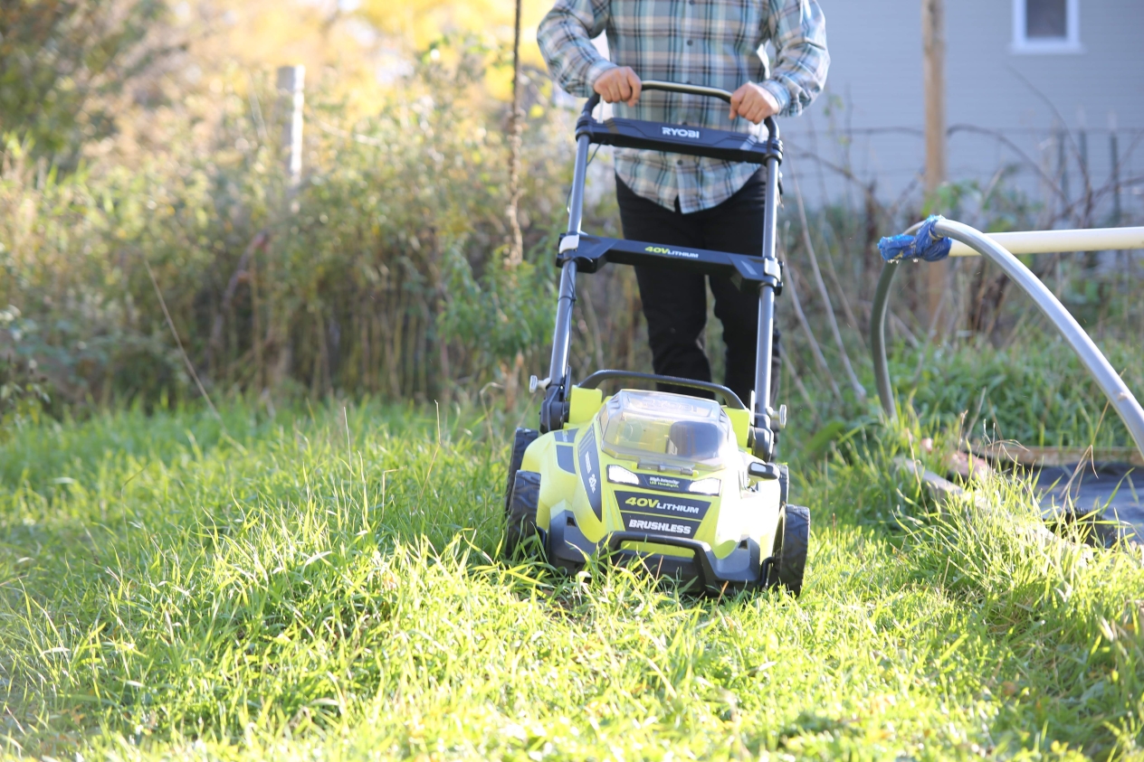 Person cutting grass with an electric lawnmower