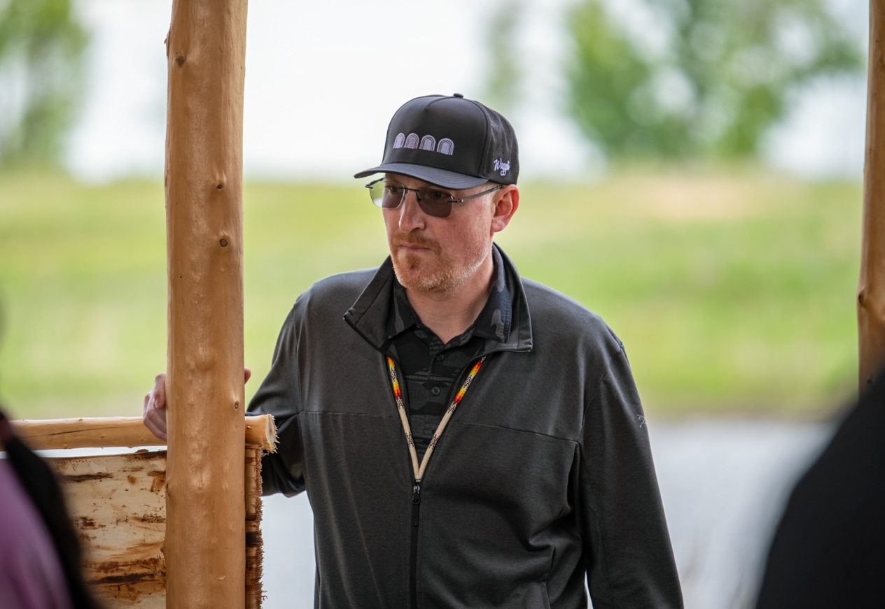 A man wearing glasses and a black cap looking to the left.
