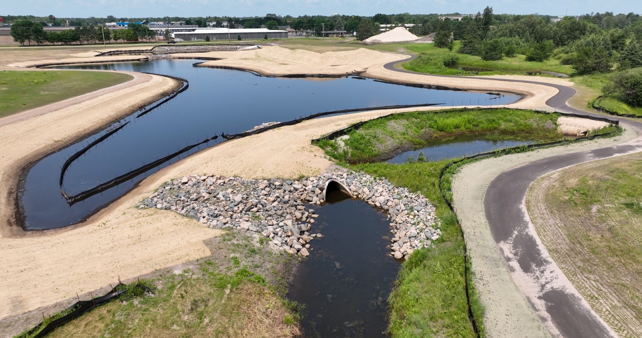 Aerial view of small stormwater ponds surrounded by erosion control blankets and a walking path on the right side.