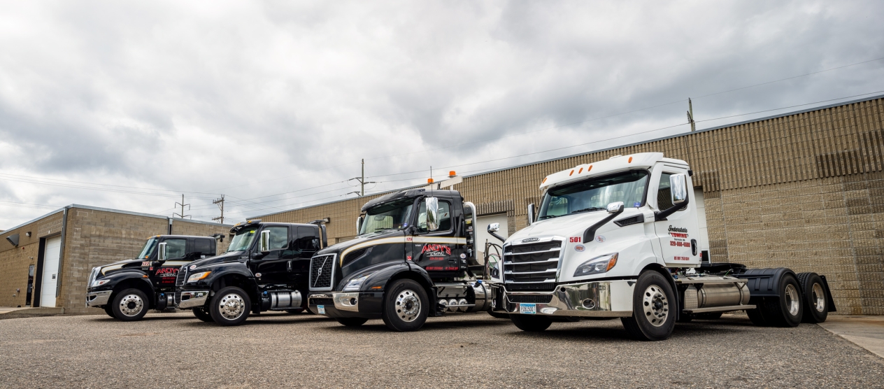Four heavy-duty clean diesel trucks parked side by side. 