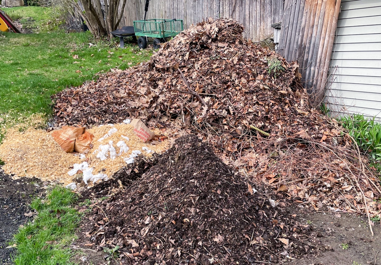 Compost piles in various stages of the composting process from sticks and dead leaves to finished soil.