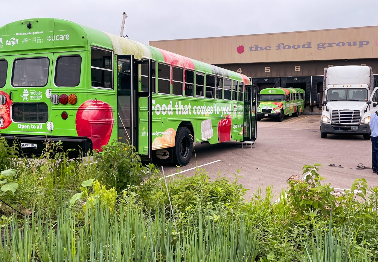 A green bus with images of food and words painted on the side that says "Food that comes to you."