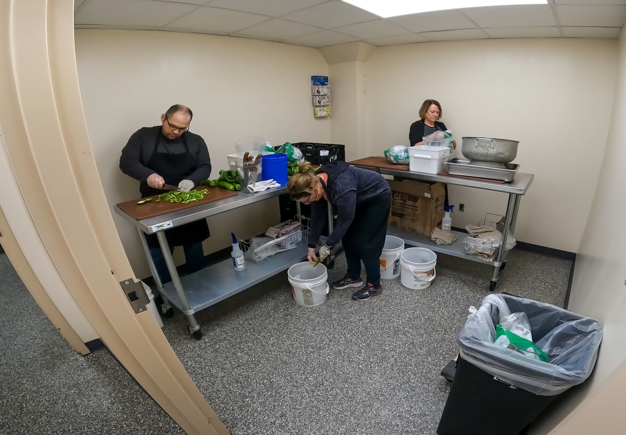 Three people prepping food for cooking.