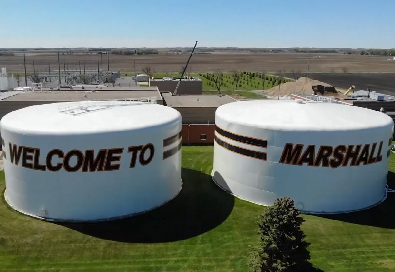 Two large white storage tanks with the words "Welcome to" and "Marshall" painted on the sides.