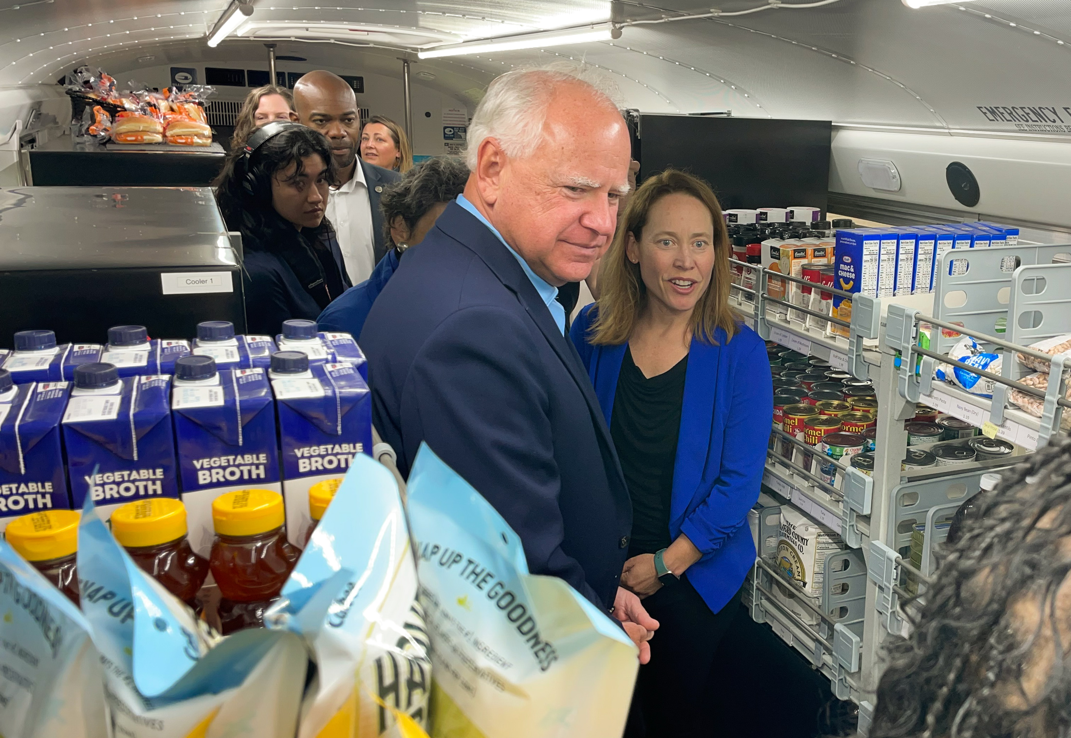 People standing in a bus lined with shelves full of food.